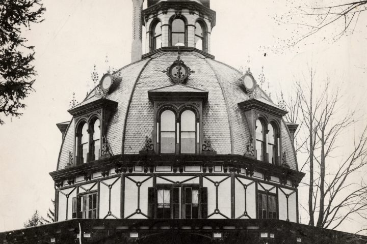 A black and white photo of a four-story building with a domed roof