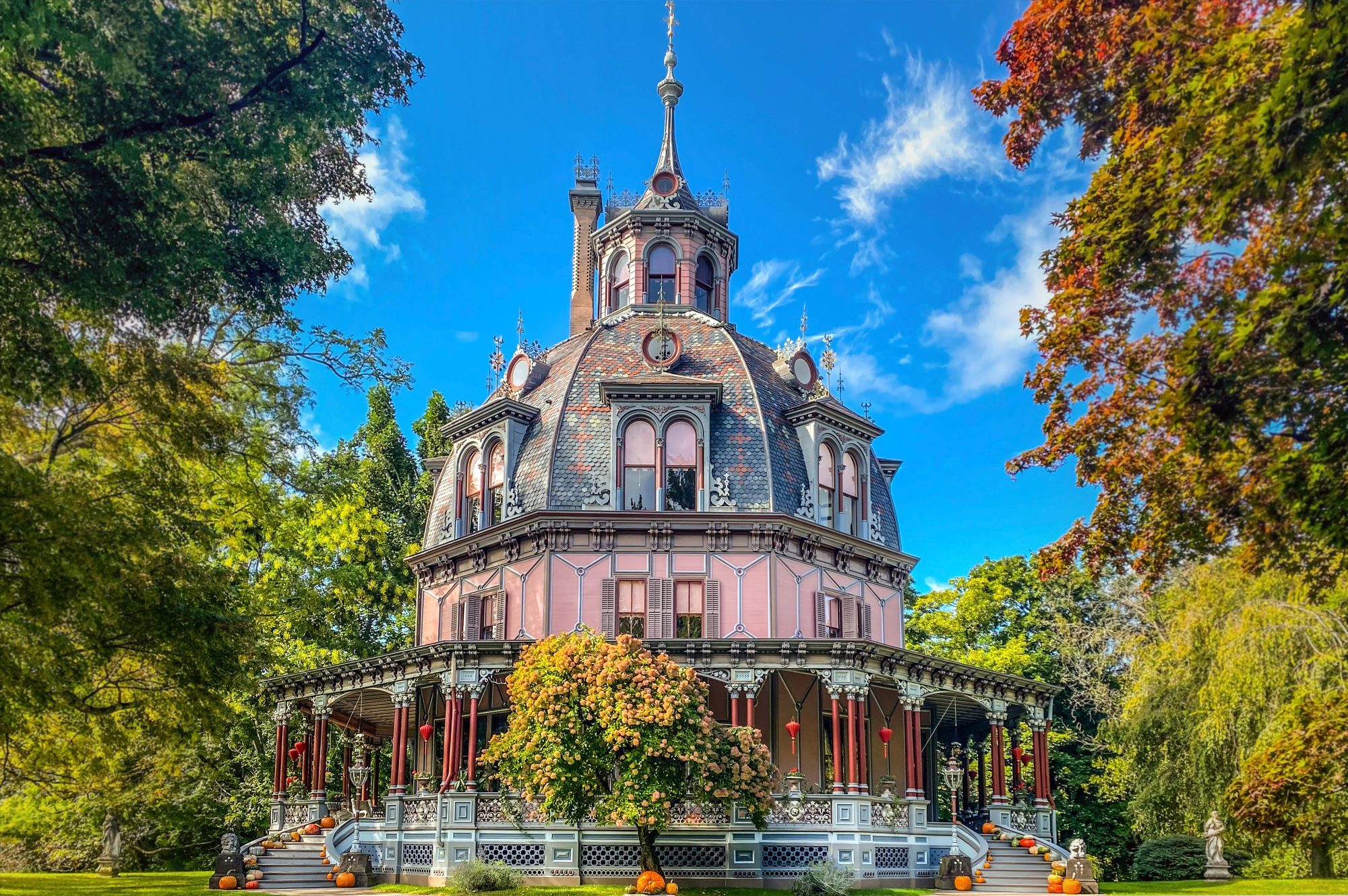 A pink, octagonal house with a gray dome appears between two large trees