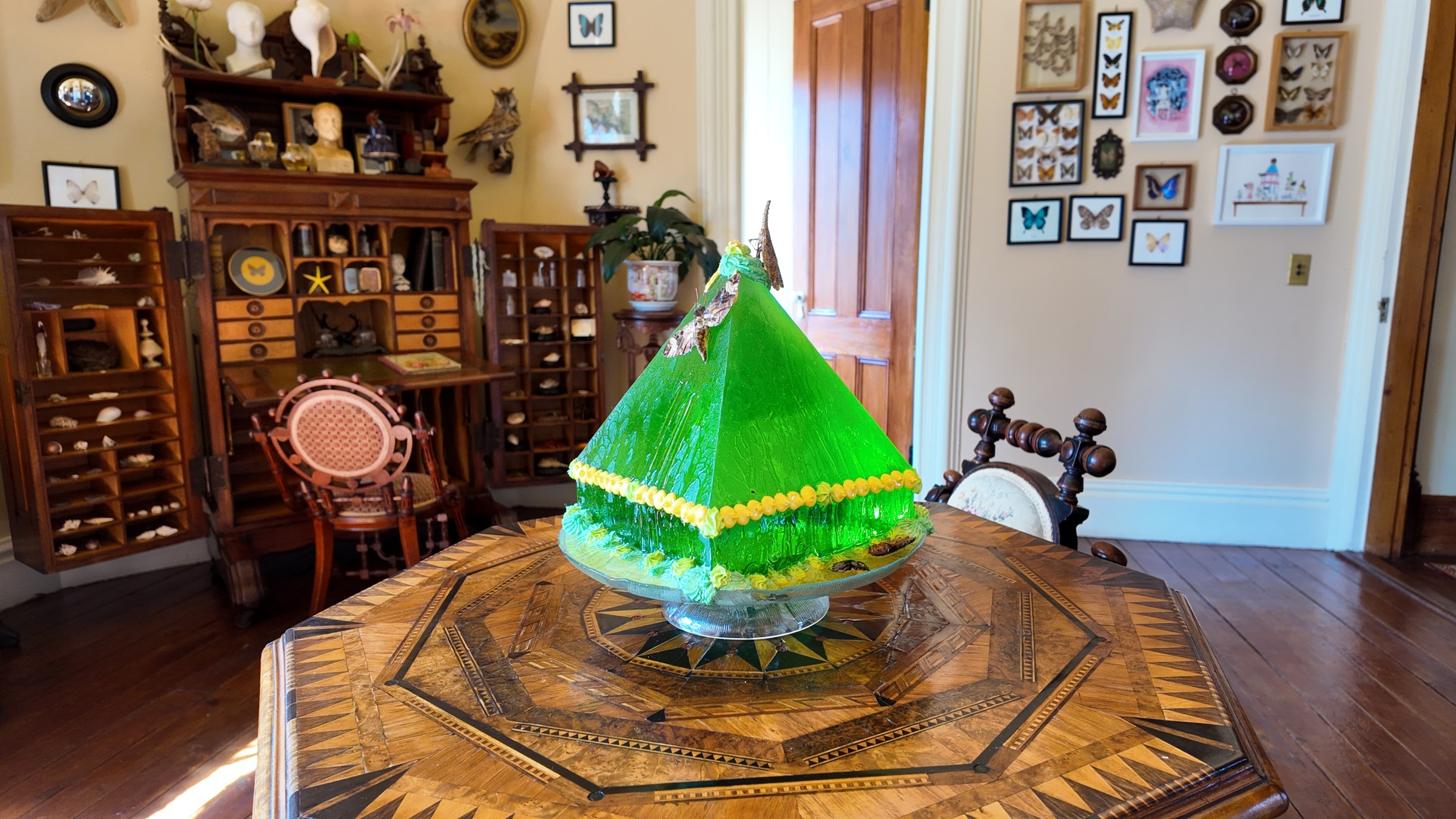 Dion-Sherwood_3 A green gelatin confection displayed on a table with furniture and framed artworks behind it.
