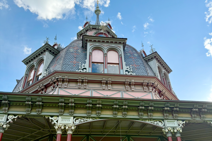 Ornate Victorian-style building with a pointed roof against a blue sky.